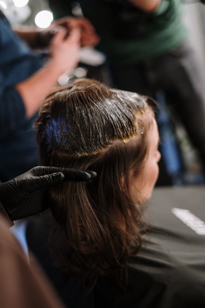 about-03 Woman receiving hair coloring treatment in a modern salon setting.