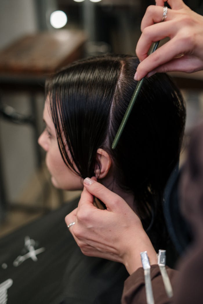 about-04 Close-up of a hairstylist sectioning a woman's wet hair in a salon.